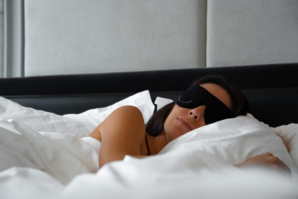 Woman sleeping in a bed with a sleeping mask